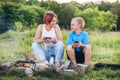 Smiling sister and brother kids have merry conversation near campfire. They looking eye to eye to each other, drinking tea from Royalty Free Stock Photo