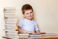 Smiling six-year-old boy in a white t-shirt and a lot of books. first grader Royalty Free Stock Photo