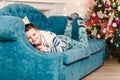 Smiling six-year-old child lies on the sofa near the Christmas tree