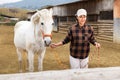 Asian horsewoman training white horse in outdoor riding arena