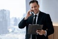 Smiling skilled businessman talking phone while looking at data. Ornamented. Royalty Free Stock Photo