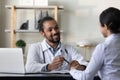 Happy African doctor consulting Indian patient in hospital. Royalty Free Stock Photo