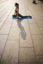 Jolly young woman exercising on mat outdoor