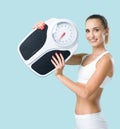 Smiling slim woman holding a weight scale