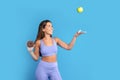 Smiling slim young caucasian woman in sportswear with donut in hand throws up green apple, has fun