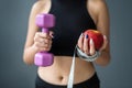 woman in holding apple and measuring tape and dumbbell standing  over gray background Royalty Free Stock Photo