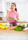 Slim young woman eating vegetable salad in home kitchen Royalty Free Stock Photo