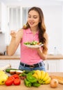 Slim young woman eating vegetable salad in home kitchen Royalty Free Stock Photo