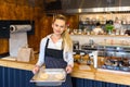 Smiling small business owner holding tray of bread dough, Happy baker with apron working in commercial kitchen Royalty Free Stock Photo