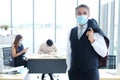 Smiling and Smart Caucasian businessman in black suit and asian teamwork wearing masks prevent covid 19 virus at office. New nomal