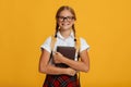 Smiling smart european teenager female student in glasses with pigtails hold books