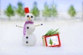 Smiling snowman and Christmas decorations in the forest during a snowfall. Xmas and New Year fairy tale background. Royalty Free Stock Photo