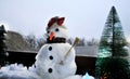 Smiling snowman near the cold windows