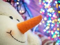 Smiling snowman`s face close-up with Christmas blurred lights in the background. Royalty Free Stock Photo