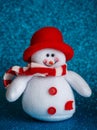 Smiling snowman toy dressed in scarf and cap on abstract bokeh background. Royalty Free Stock Photo