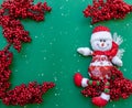 Snowman figurine on red sorb rowan branches green Christmas background Royalty Free Stock Photo