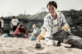 Smiling socially active woman wearing gloves gather empty coffee cups on beach