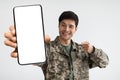 Smiling soldier in military uniform showing his cell phone, mockup Royalty Free Stock Photo