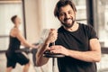 smiling sportsman leaning on iron bar with weight plates