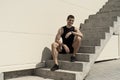 Smiling sportsman sitting at the base of ascending stairs