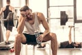 smiling sportsman sitting with bottle of water on bench press