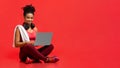 Smiling sporty athletic woman using laptop over red background Royalty Free Stock Photo