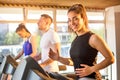 Smiling sporty girl running on treadmill in fitness center. Royalty Free Stock Photo