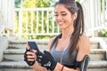 Smiling sporty girl using phone during exercise break outdoors. Royalty Free Stock Photo