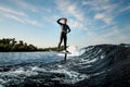 smiling sporty man in black wetsuit riding the wave on hydrofoil board