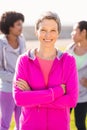 Smiling sporty woman with arms crossed in front of friends Royalty Free Stock Photo