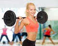 Smiling sporty woman exercising with barbell