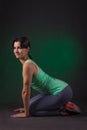 Smiling sporty woman, fitness woman sitting on a dark background with green backlight