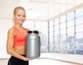 Smiling spory woman holding protein jar