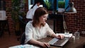 Smiling staff member planning marketing project on laptop late at night,