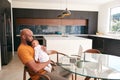 Smiling Stay At Home African American Father Cuddling Baby Daughter Whilst Working On Laptop At Home Royalty Free Stock Photo