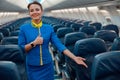 Smiling stewardess pointing at passenger seat in airplane cabin Royalty Free Stock Photo