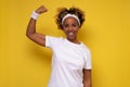 Smiling strong young african woman showing biceps muscles looking camera