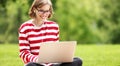 Smiling student girl in earphones using laptop  in city park Royalty Free Stock Photo