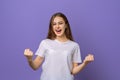 Smiling student girl making winner gesture while looking camera, standing against purple background. Celebration concept Royalty Free Stock Photo