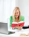 Smiling student girl reading book in college Royalty Free Stock Photo