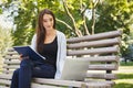 Smiling student girl sitting in park using laptop Royalty Free Stock Photo