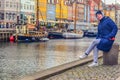 Student girl in warm winter clothes sits on the Nyhavn embankment. Copenhagen, Denmark Royalty Free Stock Photo