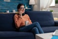 Smiling student sitting on sofa talking on smartphone.