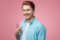 Smiling student wearing blue shirt and is gesturing vsign over pink wall Royalty Free Stock Photo