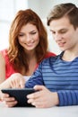 Smiling students with tablet pc at school