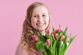 Smiling stylish child with long wavy blond hair on pink