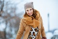 Smiling stylish female in brown hat and scarf in camel coat Royalty Free Stock Photo