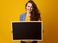 Smiling woman against yellow background showing blank board Royalty Free Stock Photo