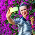 Smiling stylish woman near flowers bed taking selfie with phone Royalty Free Stock Photo