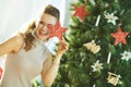 Smiling woman playing with Christmas star near Christmas tree